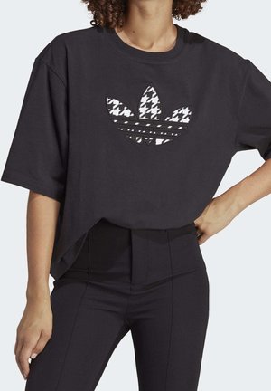 Camiseta negra de gran tamaño con un gráfico del logo de Adidas en patrón de jaquard, con cuello redondo y mangas cortas.