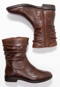 Bruna läderankelboots med en slouchy design, sidodragkedja och platt sula. Slät textur med synliga sömmar och minimala hårdvarudelarna.