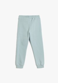 Pantalones de chándal azul claro hechos de una suave mezcla de algodón. Cuentan con una cintura elástica y puños acanalados. Textura suave y diseño ajustado.