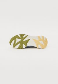Sola de sapato com um design multicolorido, apresentando secções em verde, amarelo e branco. Padrões texturizados para tração e estabilidade.