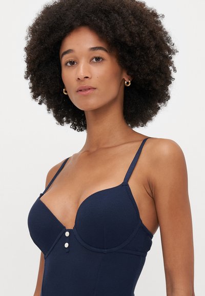 Bodies em navy com nervuras, alças spaghetti ajustáveis, decote profundo e botões decorativos na frente. Textura suave e forma ajustada.