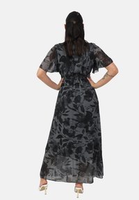Sorte blomster maxi kjole med gennemsigtig stof, korte flutterærmer og smocket talje. Længde og let fald, med et sart blomster mønster.