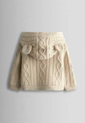 Beige strikket sweater med et struktureret kabelmønster, der har en hætte og små øre-lignende detaljer på toppen, ribkant ved nederste kant og ærmer.