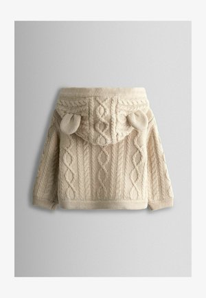 Beige kötött pulóver texturált kábelmintával, kapucnival és kis fül-szerű díszítéssel a tetején, bordázott szegéllyel és mandzsettákkal.