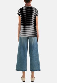 Top de rayas en blanco y negro de manga corta combinado con pantalones de denim claros de pierna ancha y zapatos beige perforados. Accesorio de bufanda al cuello detallado.