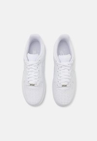 White athletic shoes featuring a textured woven pattern on the toe, smooth sides, and white laces. Simple design with minimal accents.