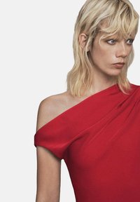 Vestido rojo de un solo hombro hecho de tela suave, con detalles drapeados en el hombro y una silueta ajustada.