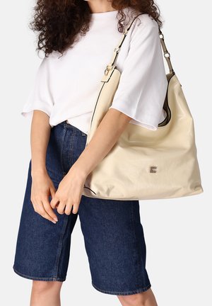 Crèmekleurige leren hobo tas met een gladde textuur, zwarte bies, zilverkleurige hardware en een geperst logo. Brede schouderriem voor comfortabel dragen.