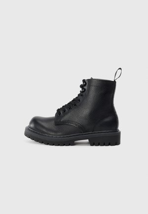 Musthave musta tekstureeritud nahk sõjaväe saabas paksu varda põhjaga, nööbid ees ja tõmbenöör kannal, näidatud külje pealt valgel taustal.