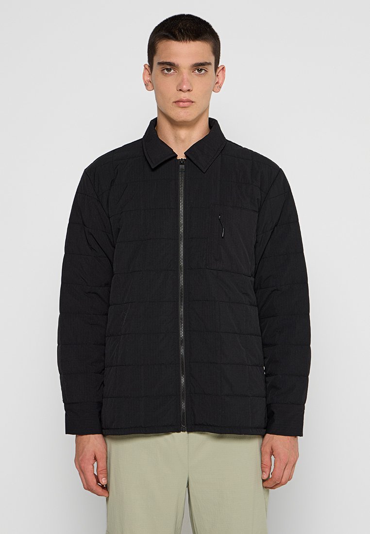 Schwarze gesteppte Jacke mit einem Kragen, Reißverschluss vorne und einer Brusttasche. Glatte Textur und lockere Passform. Schlichtes Design ohne Muster.