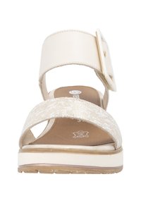 Sandale beige avec une large bride de cheville, une bande frontale texturée et une grande boucle. Tige en cuir doux avec semelle flexible. Comprend des coutures et un détail de logo.