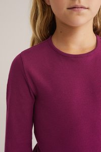 Magenta ilgo rankovėmis marškinėliai, pagaminti iš grublėtos medžiagos, su apvalia iškirpte ir siauru siluetu. Minkšta tekstūra su šiek tiek tamprumo.