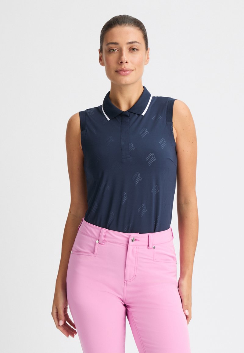 Navy ärmelloses Poloshirt mit dezentem Muster, weißen Kragenakzenten, kombiniert mit pinkfarbenen, figurbetonten Hosen. Glatte Textur und klassisches Design.