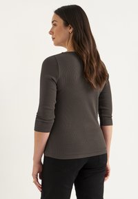 Donkergrijze geribbelde langsl sleeve top met een ronde halslijn en driekwartmouwen, gecombineerd met zwarte aansluitende broek. Minimalistisch ontwerp.