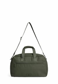 Σκούρο πράσινη τσάντα duffel με κοντά χερούλια, μακρύ ρυθμιζόμενο ιμάντα ώμου και μπροστινή τσέπη με φερμουάρ σε λευκό φόντο.