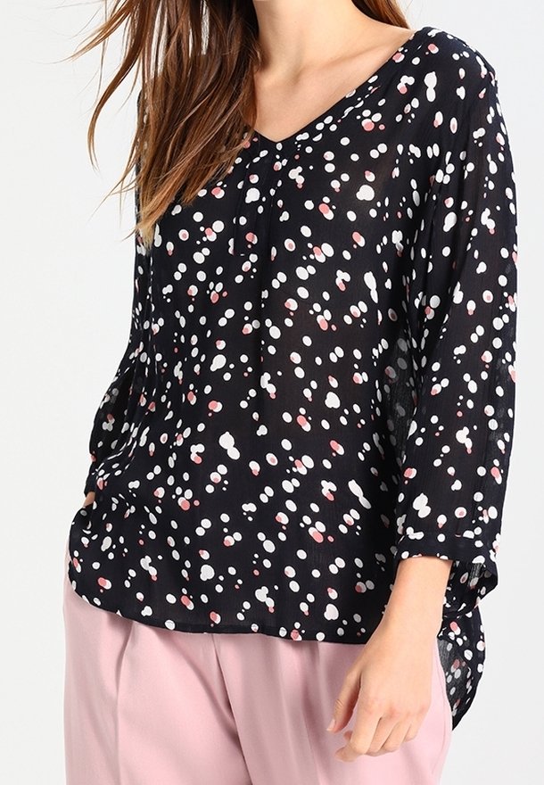 Schwarzbluse mit langen Ärmeln und V-Ausschnitt, versehen mit einem verstreuten Muster aus weißen und pinken Punkten sowie einem transparenten, leichten Stoff.