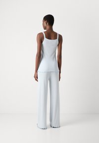 Helles blaues gestricktes Top mit dünnen Trägern, strukturiertem Design, kombiniert mit passenden ausgestellten Hosen mit Rüschensäumen.