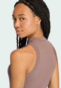 Dopasowany bezrękawnik w mauve'owym kolorze, z wysokim dekoltem i gładką fakturą, o subtelnym połysku i odsłoniętych szwach.