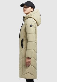 Garšs, gaiši pelēks pūkains mētelis ar plecu apgaismojumu, kapuci un melniem akcentiem; ar rāvējslēdzēju un sānu kabatām praktiskumam.