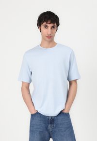 Light blue short-sleeve T-shirt in a relaxed fit, made of soft cotton fabric. Features a crew neckline and minimalistic design.