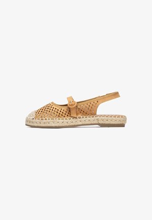 Sandalia destalonada de cuero troquelado en color beige, con punta redonda, suela trenzada de yute y detalle de botón en la tira. Tacón plano, diseño casual.