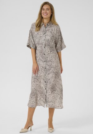 Button-down shirt dress in a light beige with black leopard print, featuring short sleeves and a loose fit, ending mid-calf.