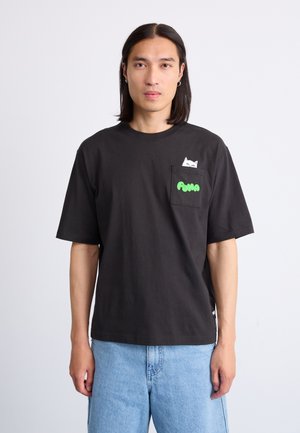 Zwarte katoenen t-shirt met korte mouwen, voorzien van een witte kattenafbeelding op de borstzak en groene tekst met de opdruk "PUMA". Eenvoudig ontwerp, ontspannen pasvorm.