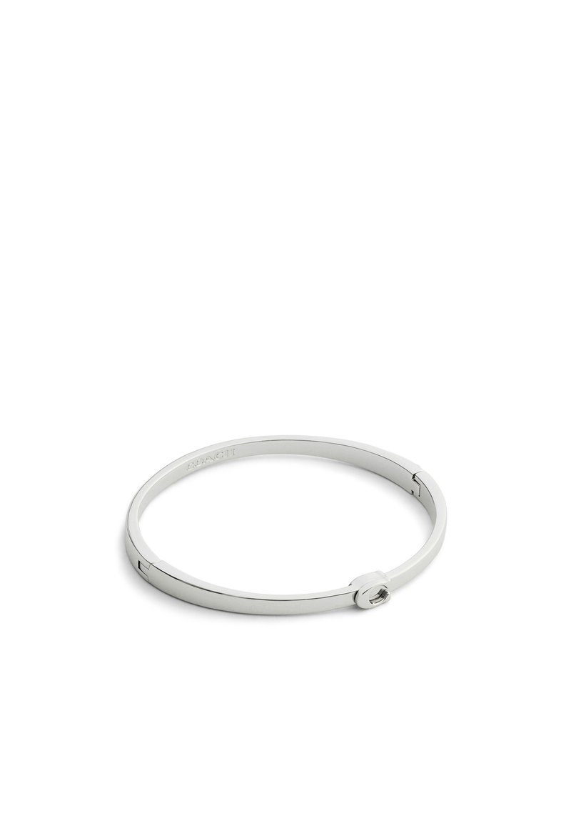 Brazalete de metal plateado con un diseño circular liso, un mecanismo de cierre simple y un logo de marca grabado.
