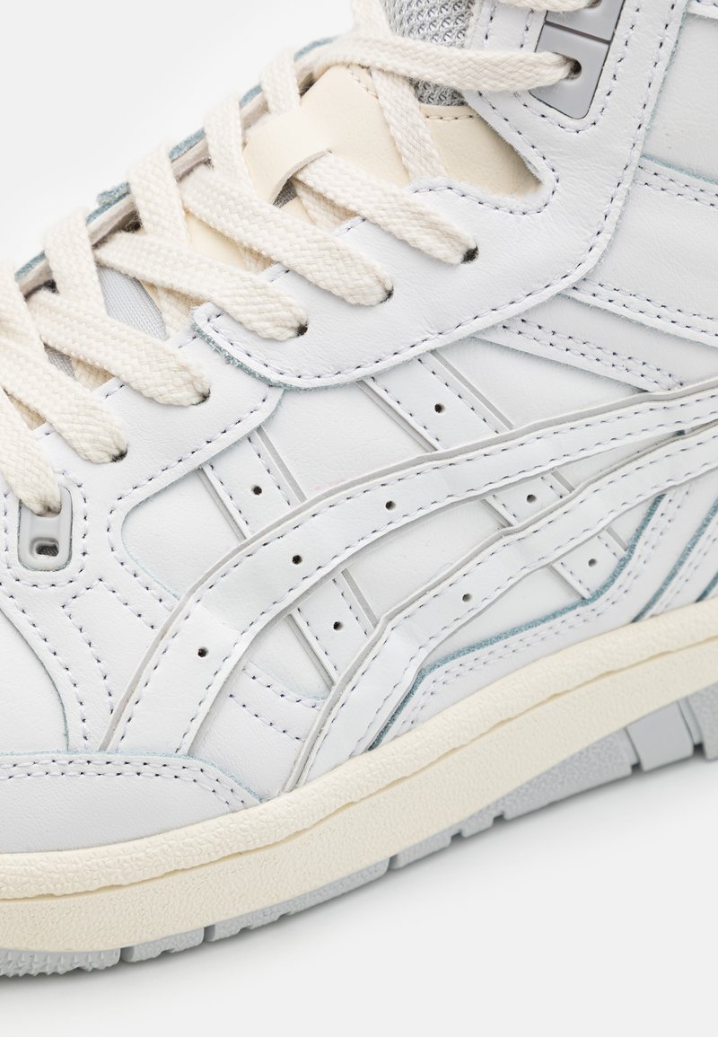 Weißer Ledersneaker mit strukturierten Akzenten, cremefarbenen Schnürsenkeln, Perforationen und einer grauen Gummisohle. Verfügt über ein geschichtetes Design und Nähdetails.