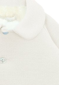 Abrigo de punto color crema con un gran cuello, forro interior suave y un solo botón iridiscente en la parte delantera.