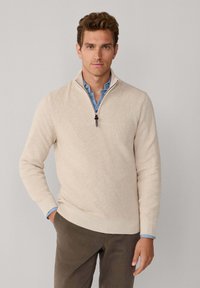 Beige geribde trui met een halve rits kraag, voorzien van een V-vormig ontwerp en een gladde textuur. Draag dit over een lichtblauw shirt en combineer het met donkere broeken.