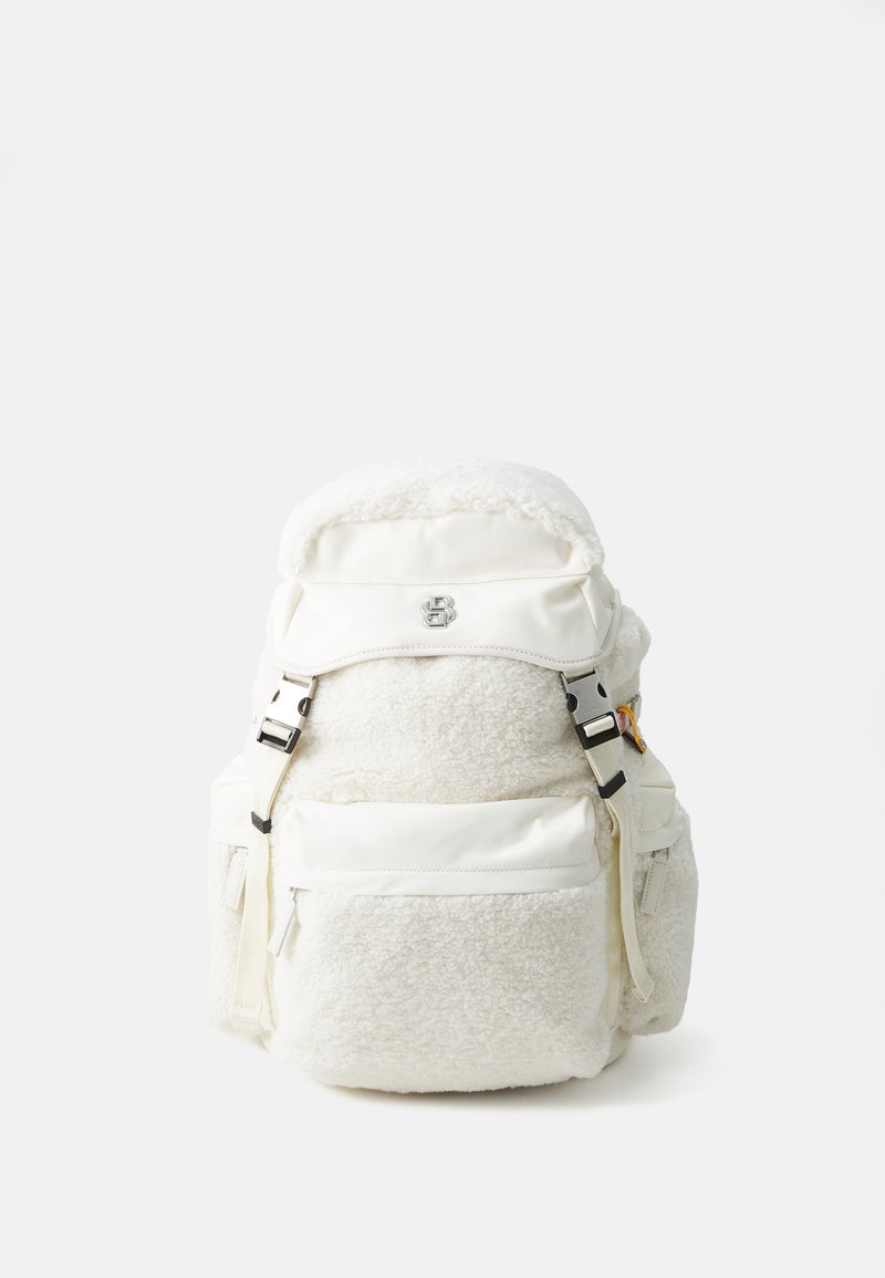 White backpack featuring a plush, textured body, metallic hardware, and a smooth, sturdy top flap with adjustable straps and side pockets.