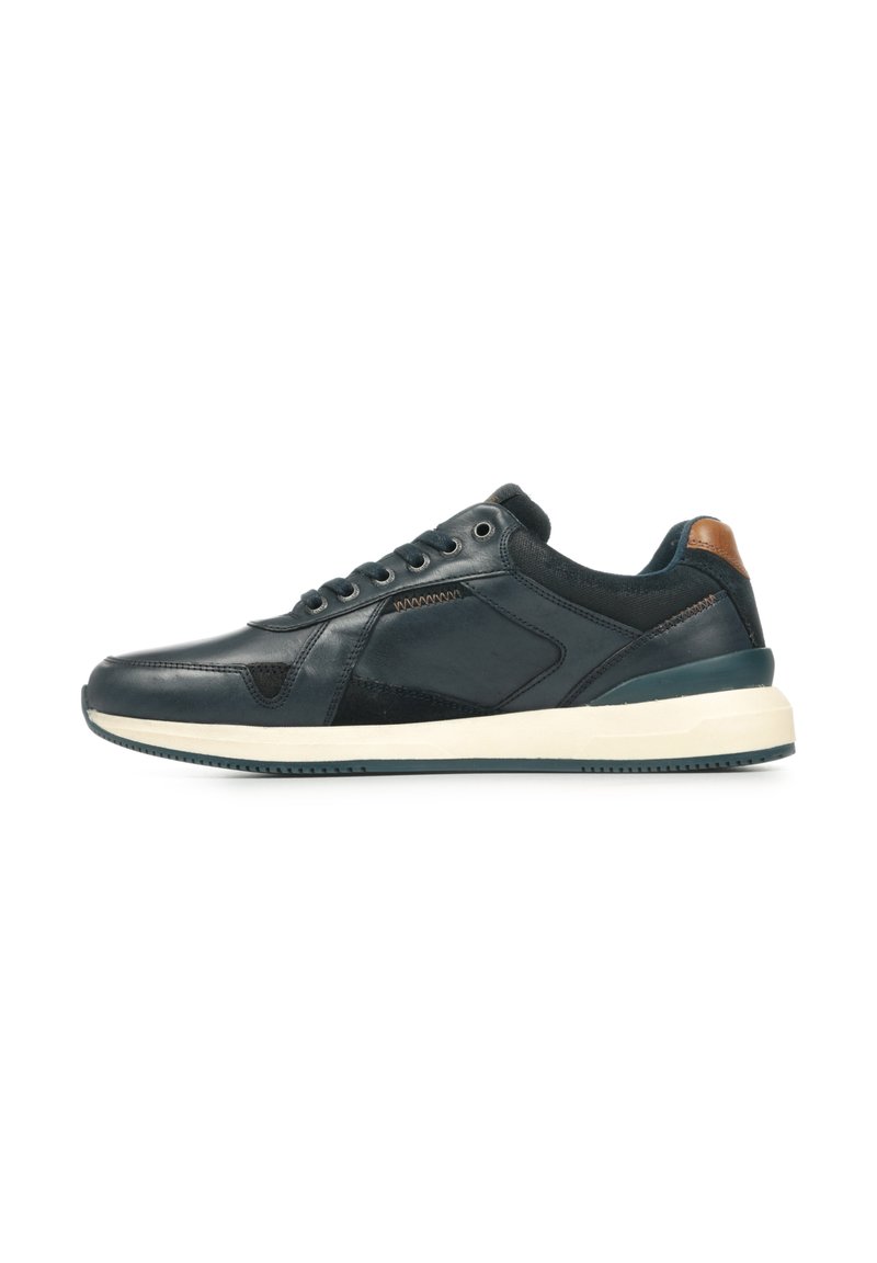 Zapatilla de cuero azul marino oscuro con textura suave, suela de goma blanca y acento de cuero marrón en el talón. Cuenta con diseño con cordones y paneles laterales.