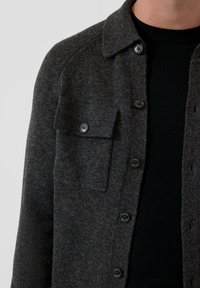 Ciemnoszara koszula-kurtka z mieszanki wełny, z przodem zapinanym na guziki, kieszenią na piersi i kołnierzykiem. Gładka tekstura i casualowy design.