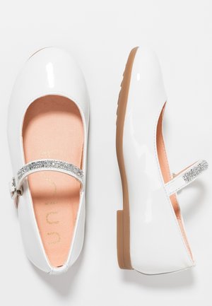 White patent leather Mary Jane shoes with sparkly straps and tan rubber soles, shown from top and side views.