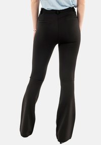 Leggings negros de campana hechos de tela elástica, con una textura suave, un ajuste entallado y dos bolsillos traseros.