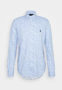 Jasnoniebieska bawełniana koszula z długim rękawem, z białym kwiatowym wzorem, kołnierzykiem zapinanym na guziki i małym ciemnym emblematem na lewej piersi.