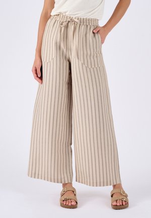 Beigeweite Hose mit dünnen vertikalen Streifen, elastischem Bund mit Kordelzug, vordere aufgesetzte Taschen, getragen mit beigen Sandalen mit Schnalle.