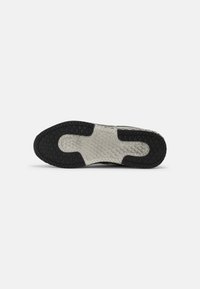 Rubber shoe sole with textured black and gray pattern; features a smooth center with a geometric design for traction.