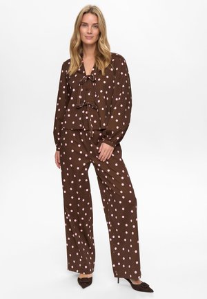 Brun bluse med prikker og matchende viddebukser lavet af blødt stof, med et sløjfedetalje og lyserøde cirkler.