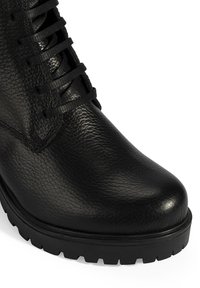 Zwart leren laars met een gestructureerde afwerking, ronde neus en zwarte veters. Stevige zwarte rubberen zool met antislipdetails.