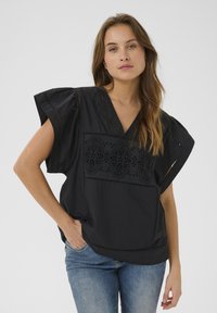 Fekete pamut blúz laza, hullámzó ujjal, elől csipke részletekkel. V-nyakú fazon, kényelmes szabású, oldalsó zsebekkel.