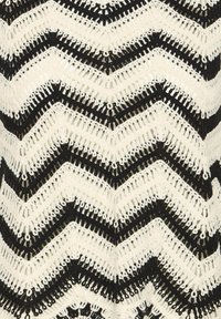 Tissu crochet noir et blanc avec un motif chevron en zigzag répétitif dans des couleurs alternées.