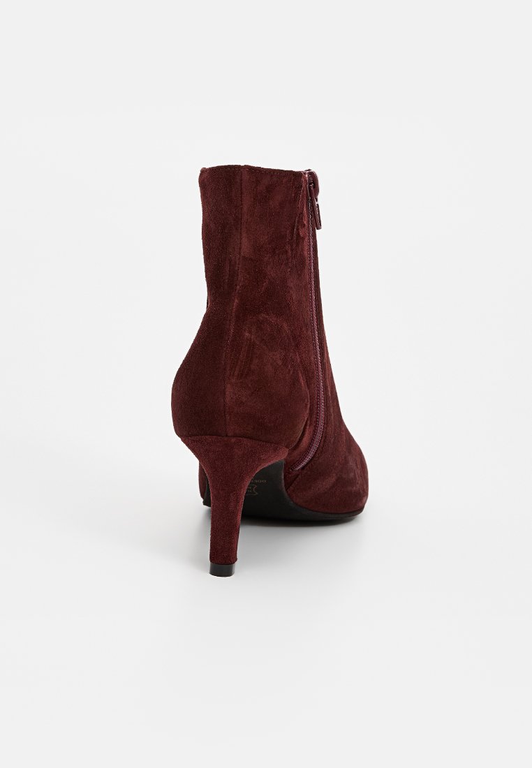 Burgundowe zamszowe botki za kostkę z wąskim, wysokim obcasem i zapięciem na suwak z tyłu. Gładka faktura z dopasowaną sylwetką.