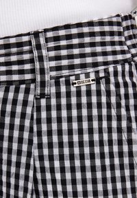 Schwarz-weiße Karotten-Shorts mit einem Knopfverschluss, versehen mit einem Etikett mit dem Text "BIG STAR" und einem sichtbaren Bunddesign.