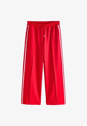 Czerwone spodenki sportowe z elastycznym pasem i sznurkiem, z białymi paskami po bokach, luźnym krojem i gładką teksturą materiału.