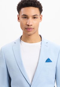Lichtblauw blazer gemaakt van gemercerweefsel, met een smalle notch-lapel en een blauwe pochet. Draag het over een wit t-shirt.