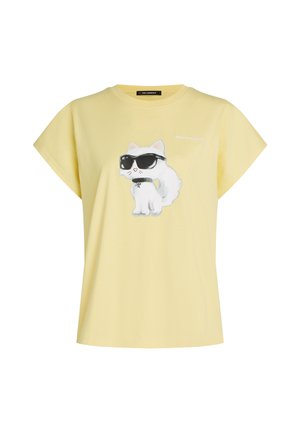 Rumena majica sredi katere je odtisk belega mačka, ki nosi črna sončna očala in ovratnico, nad mačkom pa je majhen napis "Karl Lagerfeld".