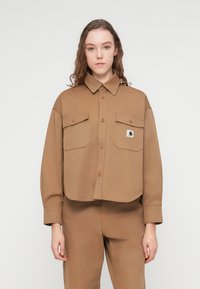 Καφέ κοντομάνικο πουκάμισο από υφασμάτινη υφή, με κλασικό γιακά, κλείσιμο με κουμπιά και δύο μπροστινές τσέπες με καπάκια και κουμπιά.