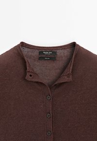 Bordeauxrode linnen henleyshirt met een geribbelde textuur, een knoopsluiting met drie knopen en een licht verweerde kraag.